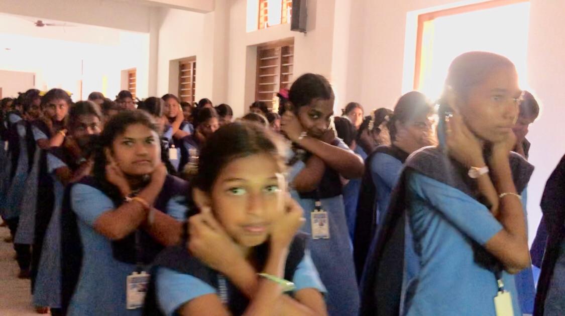 Positioning of fingers on earlobes - Workshop on Super Brain Yoga at Vivekananda Kendra Matric Higher Secondary School, Kanyakumari, Tamil Nadu state.