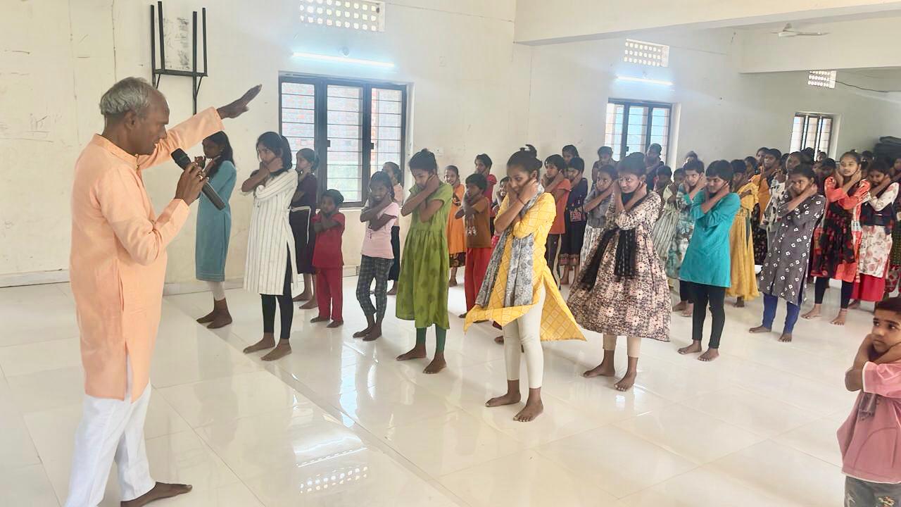 Positioning of fingers on earlobes = Demonstration on Super Brain Yoga at Manavatha Sadan, Dichpally organized by National service Scheme as part of 100 days action plan.