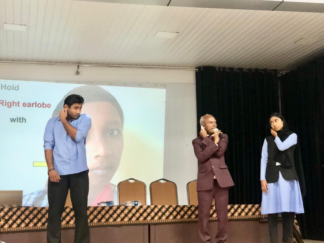Positioning of fingers on earlobes Demo - Workshop on Super Brain Yoga at MES Ponnani College, Ponnani, Kerala state. organized by Sattava Yoga & Meditation Club, Dept. of Physical Education & Legacy Wisdom Circle, Center for IKS.